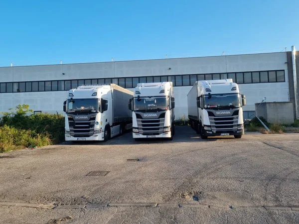 Trzy ciągniki WAAN Transport przed halą logistyczną